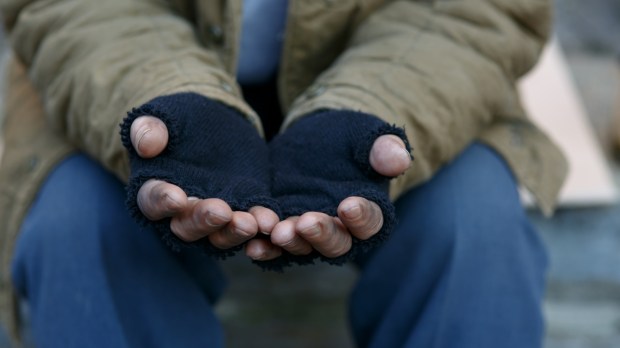 człowiek bezdomny wyciąga ręce w geście prośby o pomoc