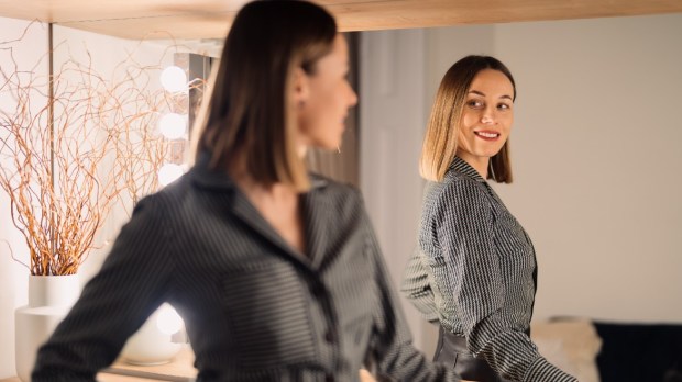 ubrana w biznesowy strój kobieta z uśmiechem przegląda się w lustrze