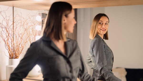ubrana w biznesowy strój kobieta z uśmiechem przegląda się w lustrze