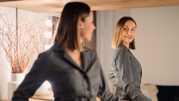 ubrana w biznesowy strój kobieta z uśmiechem przegląda się w lustrze