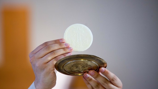 Ksiądz podnosi do góry Eucharystię