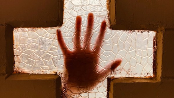 dłoń położona na szybie okna w kształcie drzwi