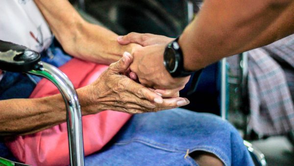 man holds old woman's hands