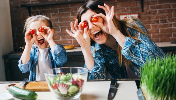 Matka wygłupia się z córką podczas wspólnego przyrządzania sałatki w kuchni