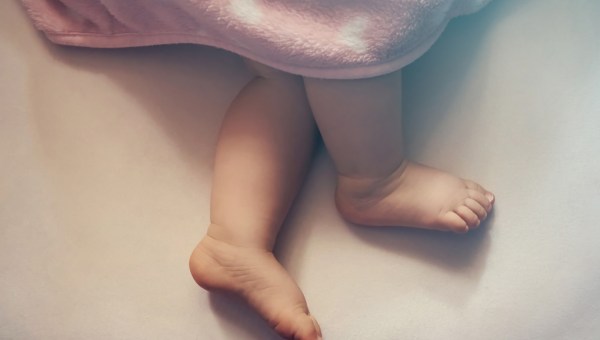 nogi niemowlaka leżącego pod kocykiem