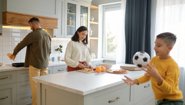 rodzice przygotowują posiłek w kuchni, podczas gdy ich syn bawi się piłką do piłki nożnej
