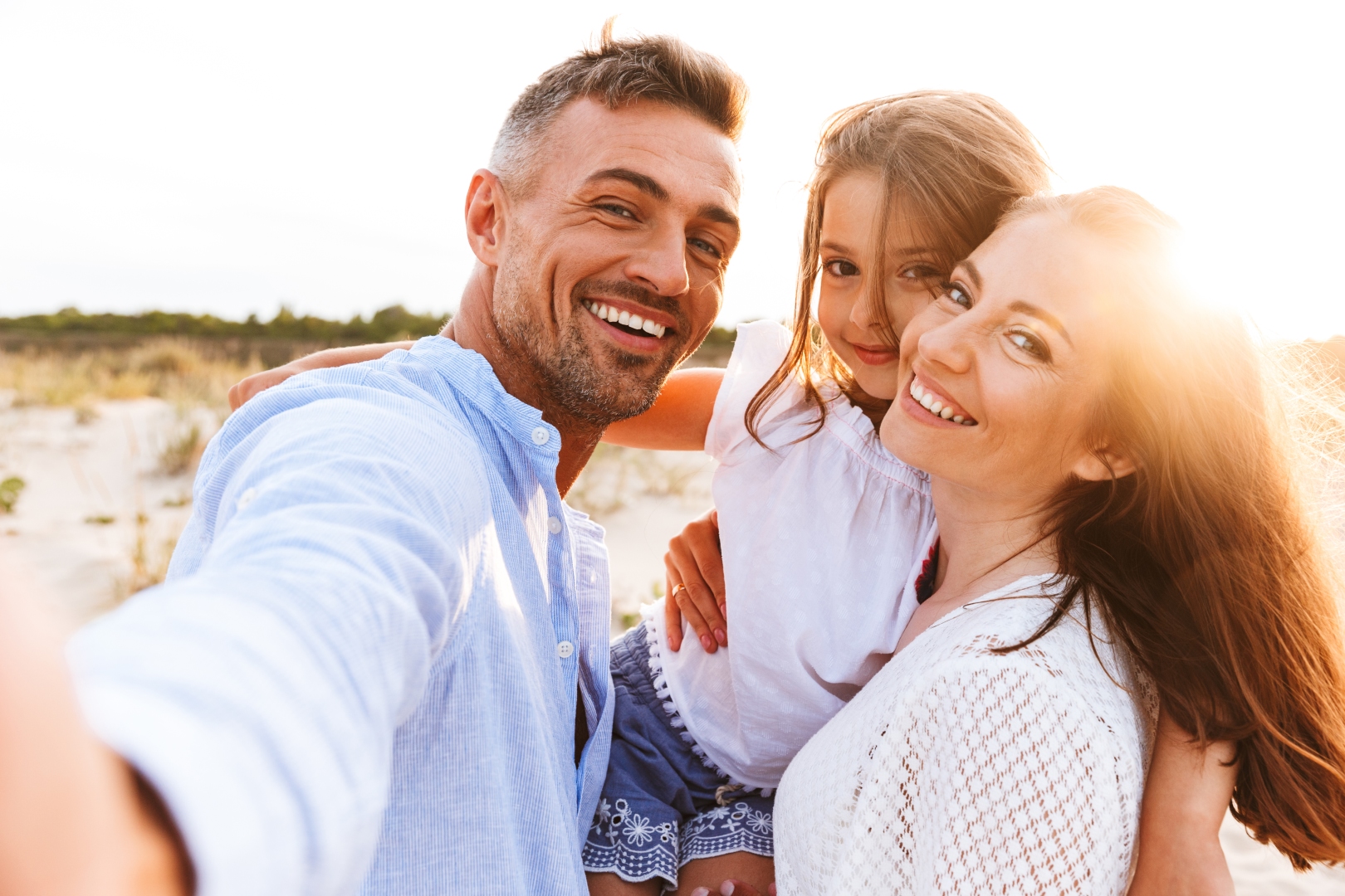 szczęśliwa, uśmiechnięta rodzina spędza czas na plaży i robi sobie zdjęcie selfie