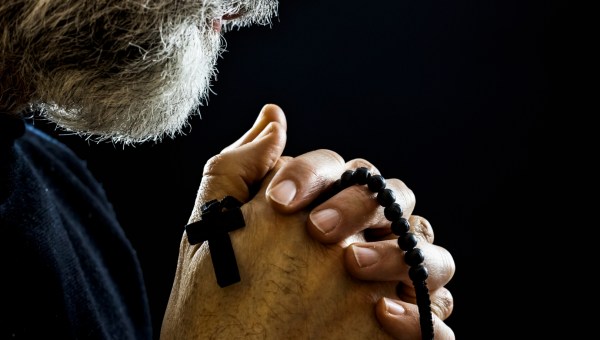 zbliżenie na mężczyznę modlącego się na różańcu