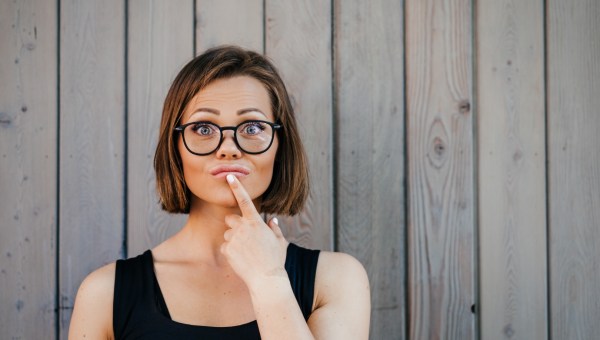 samotna kobieta usilnie zastanawia się nad czymś trzymając palec wskazujący na podbródku
