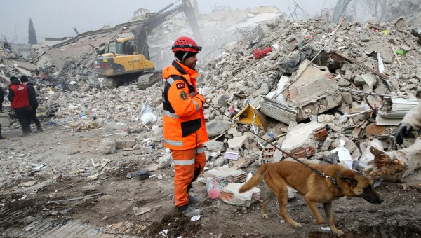 Ratownik z psem przeszukuje gruzy w poszukiwaniu ocalałych po trzęsieniu ziemi w Turcji i Syrii