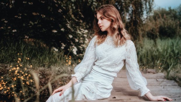 young woman in a white dress sitting on the pier