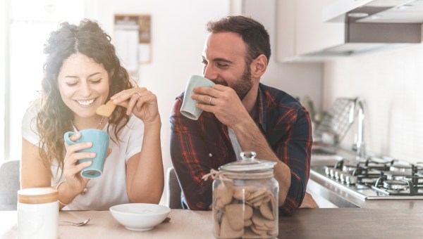 małżeństwo rozmawia w kuchni popijając kawę i ciesząc się byciem razem