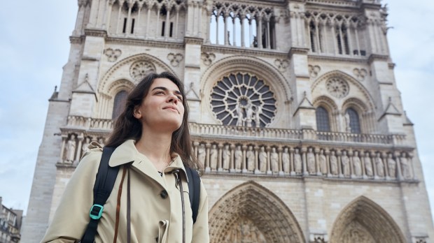 młoda turystka stoi przed fasadą katedry Notre-Dame w Paryżu