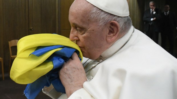Papież Franciszek całuje ukraińską flagę podczas pokazu filmu dokumentalnego na temat wojny na Ukrainie
