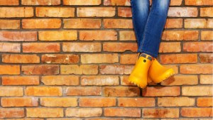 nogi dziewczyny w jeansach siedzącej na murze wzniesionym z pomarańczowych cegieł