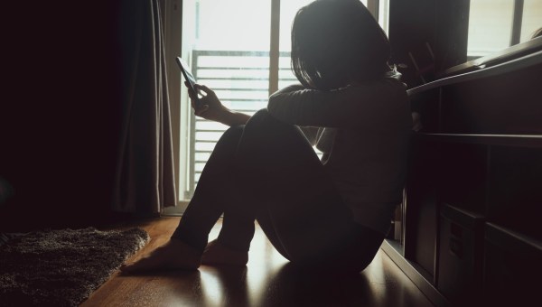 zdesperowana kobieta sięga po telefon, by zadzwonić po pomoc