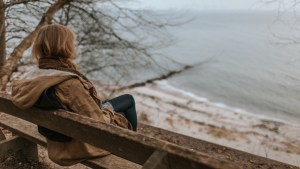 smutna kobieta siedzi na ławca nad brzegiem morza