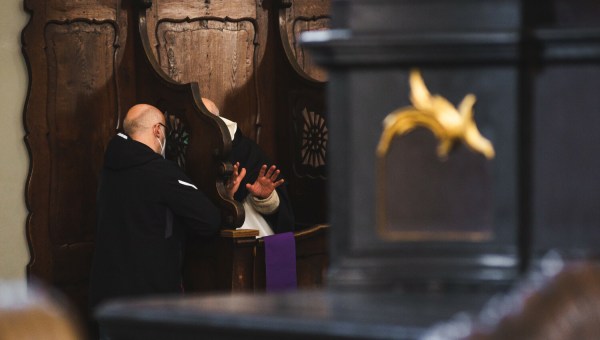 Ksiądz i penitent w konfesjonale podczas spowiedzi