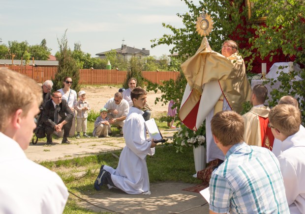 Priest holds up monstrance in outdoors Eucharistic procession