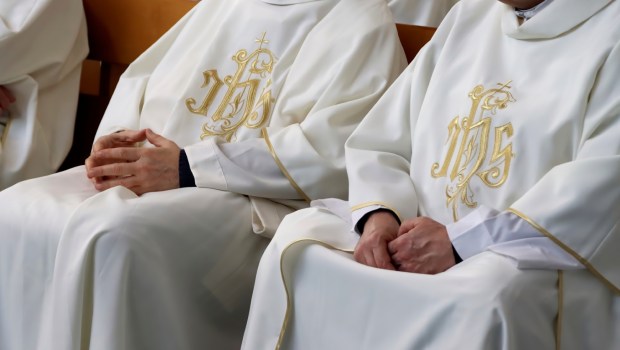 Księża siedzący na krzesłach podczas Mszy świętej