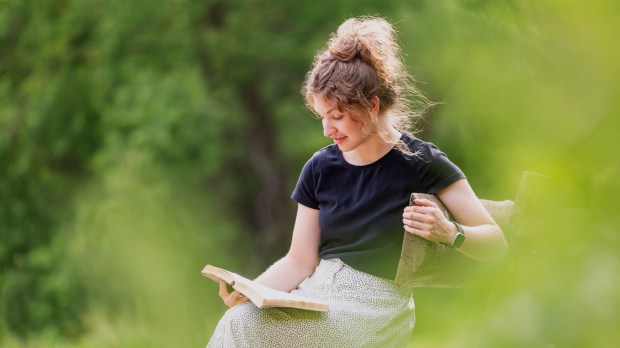 kobieta czyta Pismo Święte na ławce w parku
