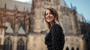 Uśmiechnięta młoda dziewczyna stoi przed katedrą w czeskiej Pradze