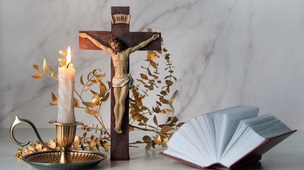 Krzyż i świeca ustawione na stole przed modlitwą wieczorną