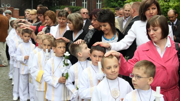 Chłopcy idący do pierwszej Komunii świętej czekają przed wejściem do kościoła wraz z rodzicami