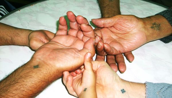 Dłonie mężczyzn z wytatuowanym krzyżem koptyjskim złożone jedna na drugiej