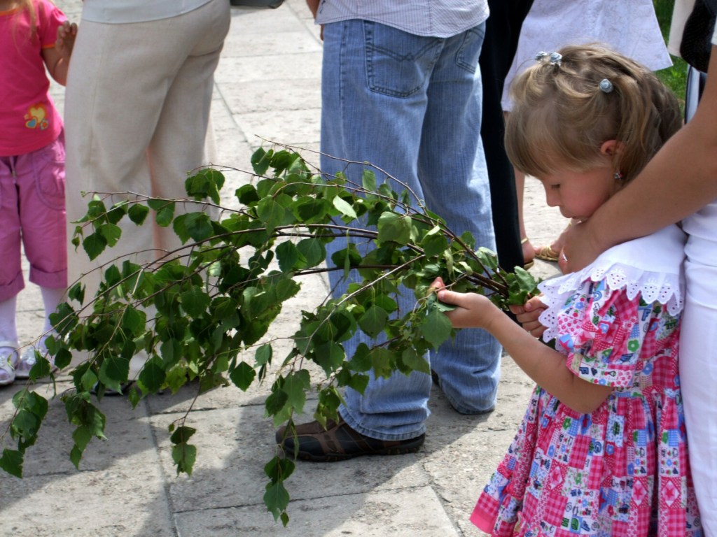 Dziewczynka trzyma gałązkę brzozy podczas procesji Bożego Ciała
