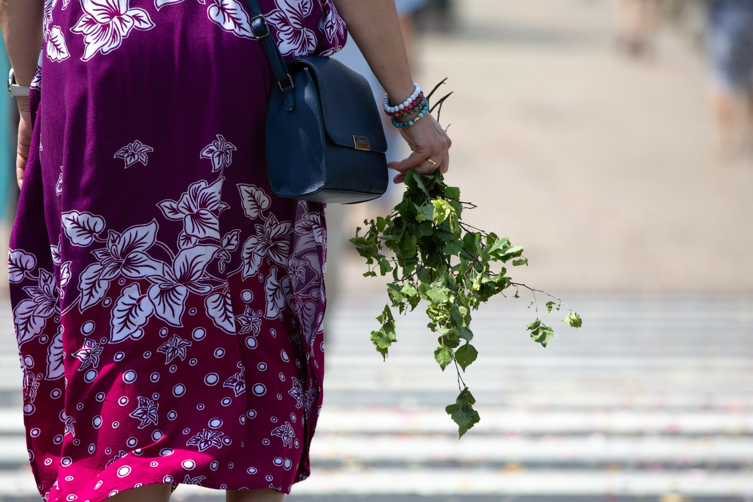 Kobieta trzyma w ręku oderwaną gałązkę brzozy w dniu Bożego Ciała