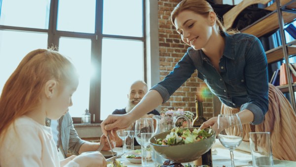 Matka nakłada sałatkę córce podczas rodzinnego posiłku