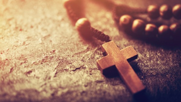 Rosary with wooden cross on stone background