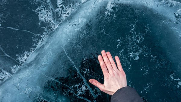 Dłoń dotykająca powierzchni zamarzniętego jeziora