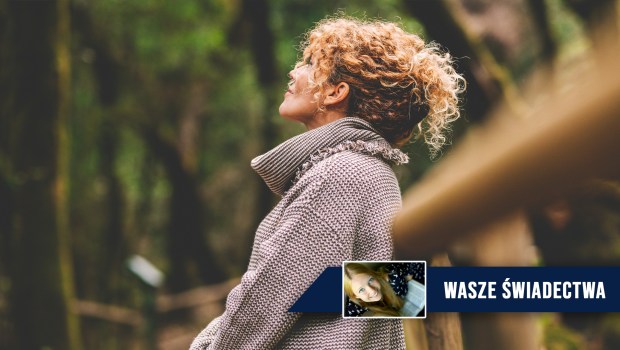 Kobieta w średnim wieku zatrzymała się podczas spaceru w lesie i spogląda w górę ze spokojem