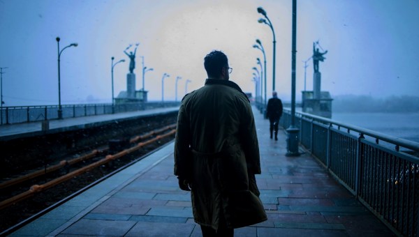 Mężczyzna w mglisty, ponury dzień idzie przez most