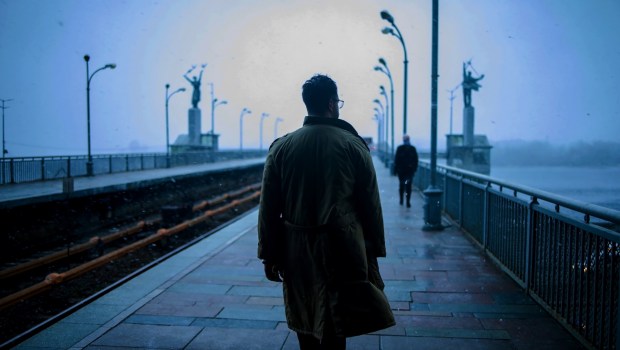 Mężczyzna w mglisty, ponury dzień idzie przez most