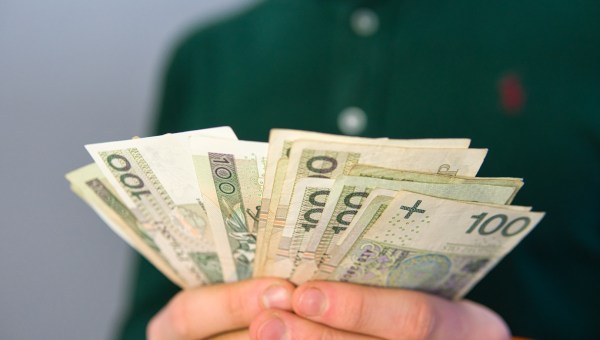Plik polskich banknotów w męskich dłoniach