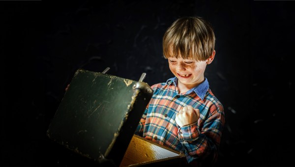 Uradowany chłopiec otwiera starą walizkę znalezioną na strychu