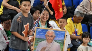 A woman holds an artwork portrait of Pope Francis as the faithful gather to attend mass led by the pope at the Steppe Arena in Ulaanbaatar