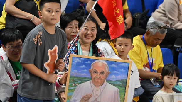 A woman holds an artwork portrait of Pope Francis as the faithful gather to attend mass led by the pope at the Steppe Arena in Ulaanbaatar