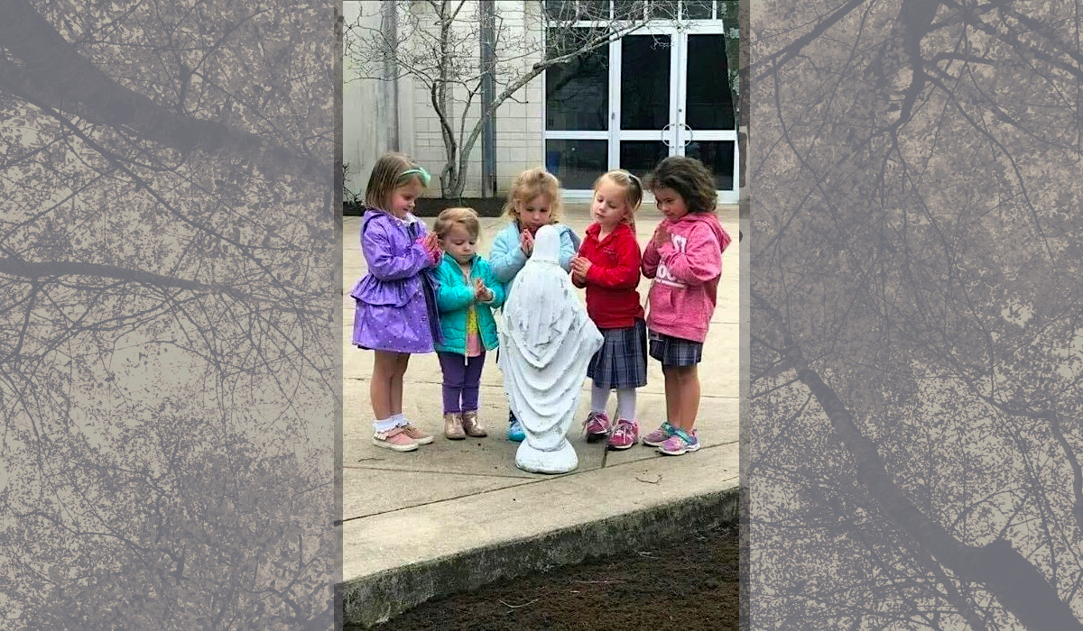 Małe dziewczynki modlą się przy figurce Maryi