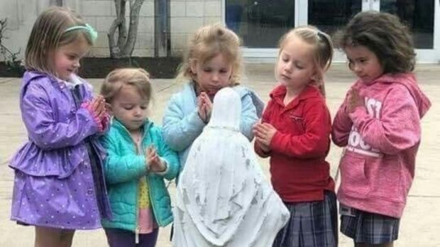 Małe dziewczynki modlą się przy figurce Maryi