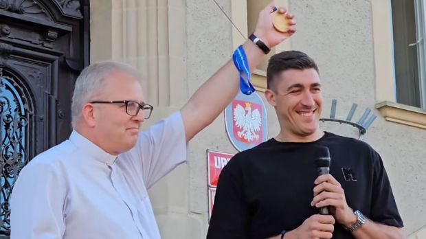 Łukasz Kaczmarek – mistrz Europy w siatkówce - przekazuje medal ks. Aleksandrowi Genderze