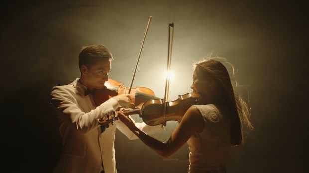 Dwoje muzyków gra razem utwór na skrzypcach