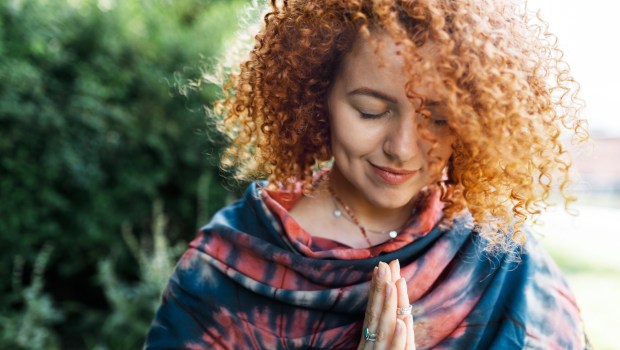 Rudowłosa kobieta modli się w parku