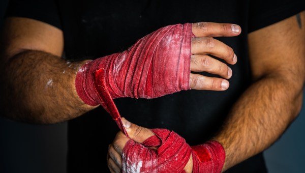 Mężczyzna owija taśmą swoje dłonie przed rozpoczęciem walki