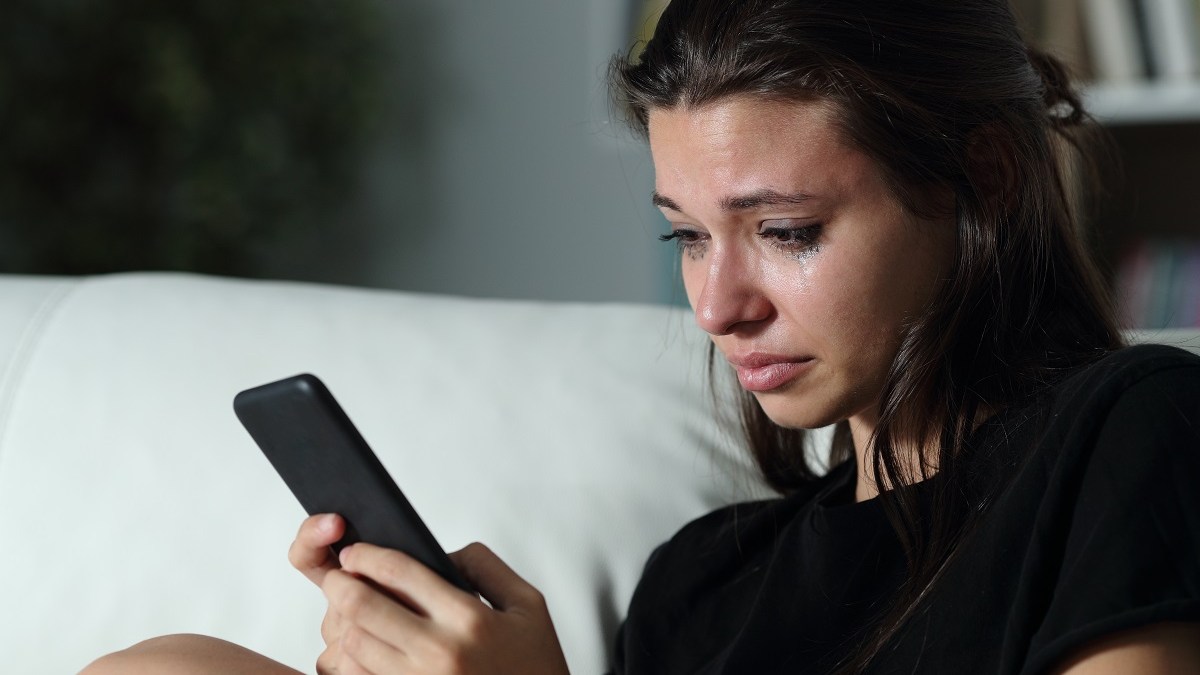 Woman watching phone tears