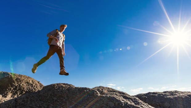Mężczyzna z plecakiem biegnie i skacze po skałach