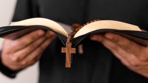 Ksiądz trzymający modlitewnik i różaniec